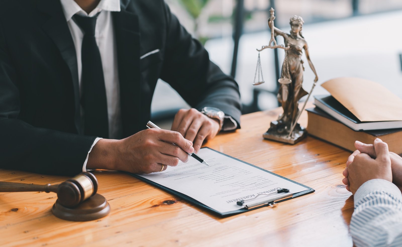 Lawyer working with client at table in office, focus on hands